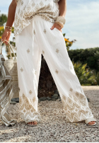 Materiałowe spodnie wide leg we wzory Sunset Paradise biało-beżowe